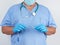 Doctor in blue uniform and latex gloves holds a plastic system for intravenous droppers