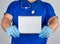 doctor in blue uniform and sterile latex gloves holding open blank notebook