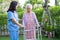 Doctor caregiver help and care Asian senior woman patient walk with walker in park at hospital