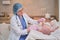 Doctor checks the throat of a newborn child with a plowshare. A nurse in uniform with a wooden stick in her hand examines the