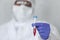 Doctor in chemical protection suit is holding blood sample fot testing it on COVID, COVID-19, coronavirus to stop