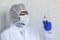 Doctor in chemical protection suit is holding syringe with blood sample fot testing it on COVID, COVID-19, coronavirus