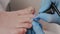 Doctor chiropodist in medical gloves paints the client's toenails with blue nail polish. Closeup. The concept of