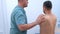 Doctor chiropractor treats patient shoulder in clinic on rehabilitation therapy.