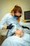 Doctor conducts procedure for rejuvenating facial skin with laser. Woman receiving facial beauty treatment, removing pigmentation