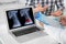 Doctor consulting man in clinic, closeup. Focus on laptop displaying x-ray of patient with cancer