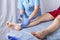 Doctor cosmetician makes the procedure shugaring sugar paste on the right ankle to a young woman