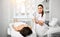 Doctor-cosmetician in white gown with a medical device is ready to perform a cosmetic procedur for a patient in beauty saloon