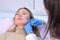 Doctor cosmetologist makes injection with filler in woman face against wrinkles.