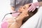 A doctor cosmetologist makes a microcurrent facial therapy to a young woman with a device in a beauty wellness salon. Cosmetology