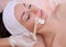 The doctor is a cosmetologist for the procedure of cleansing and moisturizing the skin, applying a mask with stick to the face of