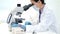 Doctor, covid or woman scientist with microscope in science lab writing DNA research, medical or medicine data analysis