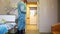 A doctor in a dressing gown opens an automatic door in the patient`s room