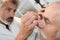 Doctor dripping eye drops to senior patient