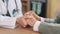 Doctor, elderly person and holding hands in closeup for support, consulting or care in clinic for wellness. Medic, nurse