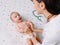 Doctor entertains baby to exam her with stethoscope on a special table