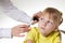 The doctor examines the ear canal of a little caucasian girl 5 years old in the doctor`s office. Diagnosis and treatment of ear