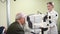 doctor examines elderly man's eye on screen of autorefractometer.
