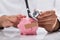 Doctor examining broken piggybank with stethoscope