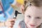 Doctor examining ear with otoscope for little smiling girl