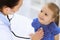 Doctor examining a little girl by stethoscope. Happy smiling child patient at usual medical inspection. Medicine and