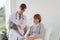 the doctor is examining the patient in the hospital. Caucasian doctor wearing gown and listening device and a female patient