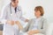 the doctor is examining the patient in the hospital. Caucasian doctor wearing gown and listening device and a female patient