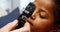 Doctor examining patients eye with otoscope