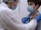 A doctor with a face mask examines a patient with a mask with a stethoscope