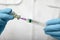 Doctor filling syringe with hepatitis vaccine from glass vial, closeup