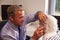 Doctor Fitting Senior Female Patient With Hearing Aid