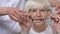 Doctor giving eyeglasses to happy elderly woman with vision problems, health