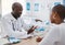 A doctor giving patient hospital information at a clinic and explaining medical benefits to a woman in his office