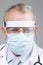 Doctor in Glasses is Wearing a Transparent Protective Face Shield, Mask and Overalls in a Hospital Room. Covid-19