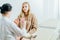 Doctor gynecologist talking to a female patient in an orange chair in a medical office.