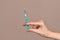 Doctor hand holding green syringe with clear fluid. Brown background. Detail of syringe