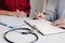 Doctor hand holding pen writing patient history list on note pad and talking to the patient about medication and treatment