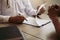 Doctor hand holding pen writing patient history list on note pad and talking to the patient about medication and treatment