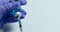 Doctor hand in latex blue protective gloves holds syringe and blue vaccine bottle liquid on blue background