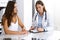 Doctor and happy patient talking while sitting at the desk. The physician or therapist discussing healthy lifestyle