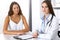 Doctor and happy patient talking while sitting at the desk. The physician or therapist discussing healthy lifestyle