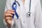 Doctor holding blue  ribbon, closeup view. Symbol of medical issues