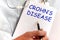 Doctor holding a card with text CROHNS DISEASE, medical concept