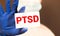 Doctor holding a card with text PTSD medical concept
