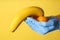 Doctor holding fruits symbolizing male sexual organ on yellow background, closeup. Potency problem