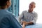 Doctor holding hands of senior man while consoling at table