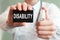 Doctor holding a paper card with text DISABILITY and the medicine bottle, medical concept