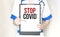 Doctor holding a paper plate with text STOP COVID, medical concept