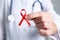 Doctor holding red awareness ribbon, closeup. World AIDS disease day