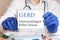Doctor holding a tablet with text: GERD. GERD - Gastroesophageal Reflux Disease, medical concept.